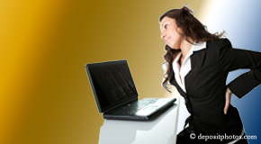 a person Richmond bending over a computer holding her back due to pain